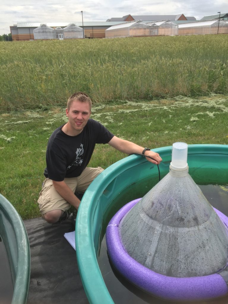 former MS student Nate Williams next to a Mesocosm tank